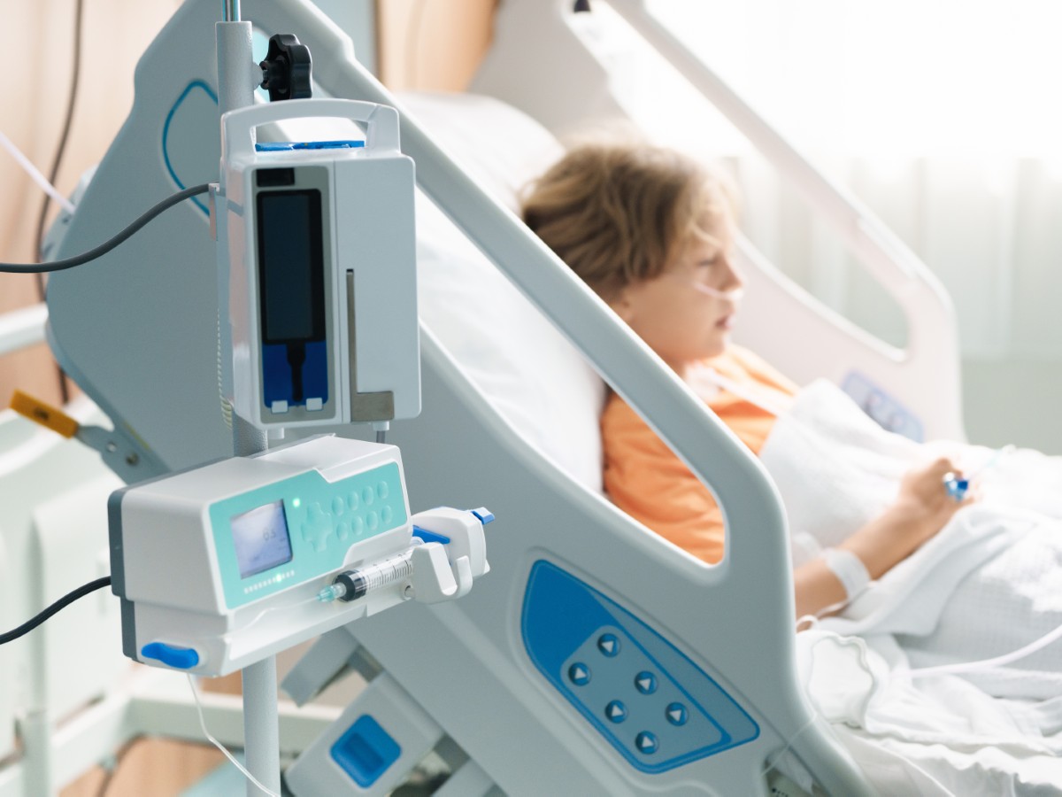 A stock image of a sick child in a hospital room with an oxygen tube and IV line.