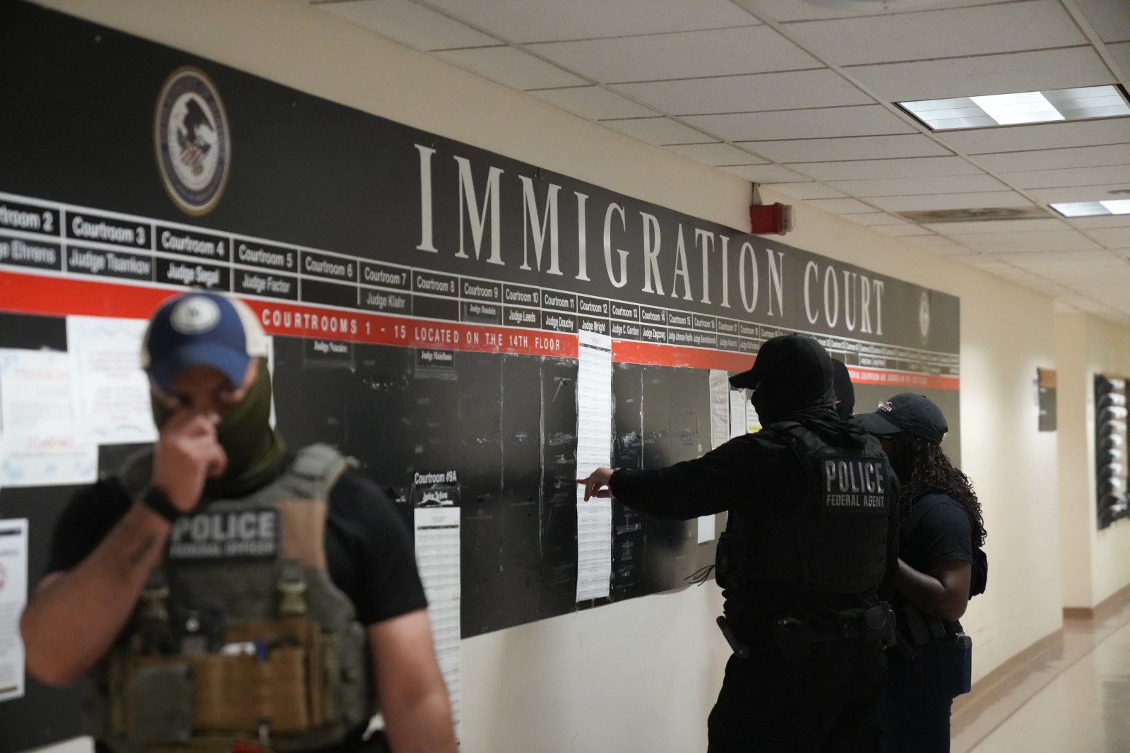 U.S. Immigration and Customs Enforcement (ICE) agents look over lists of names and their hearing times and locations inside the Federal Plaza courthouse before making arrests on June 27, 2025, in New York.